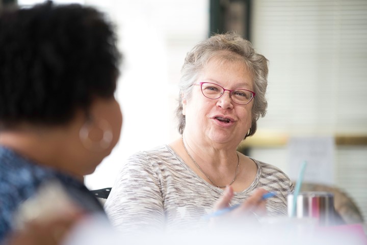 An older woman talking in a group setting.