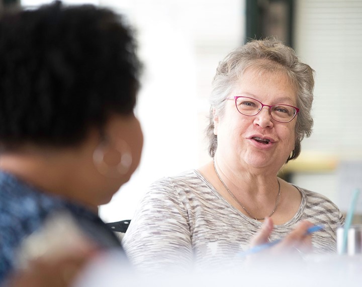 A photo of a person speaking with another person