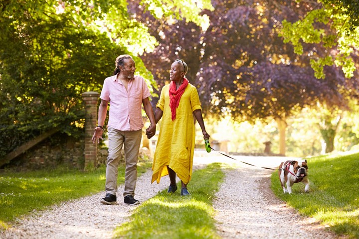 Smiling couple walking dog on a path