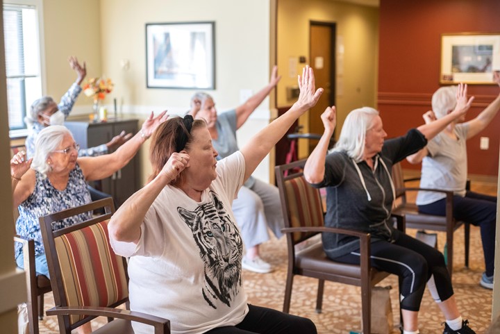 Photo of six people stretching their arms while seated.