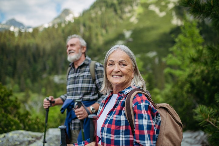 Potrait of active senior woman hiking with husband in autumn mountains.