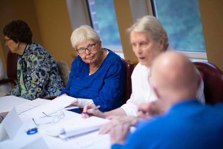 Older adults in a class discussing together at a table.