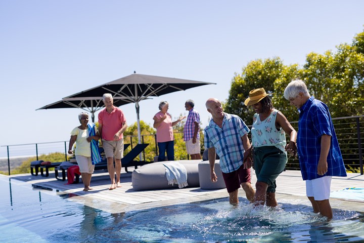 Photo of several people wading in an outdoor pool on a sunny day