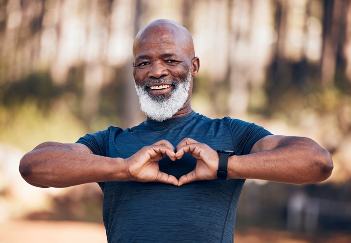 Photo of an older adult making a heart shape with their hands.