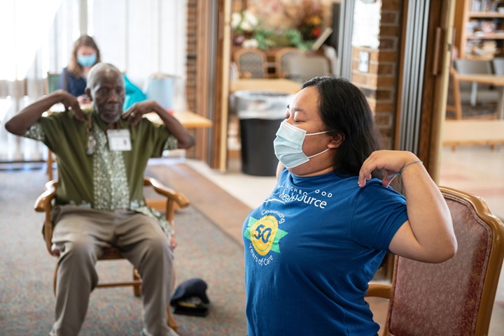 Photo of two people stretching while seated.