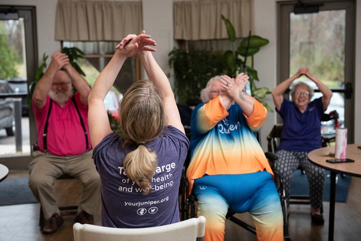 Photo of four people raising their arms above their heads while seated.