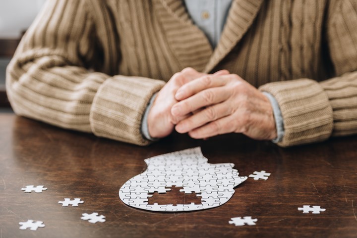 An older adult playing with a puzzle the shape of a head