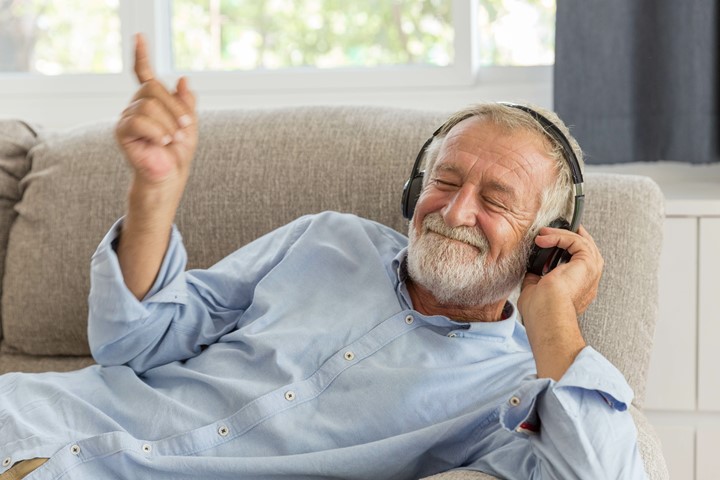 A person listening to headphones while lying down on a couch.