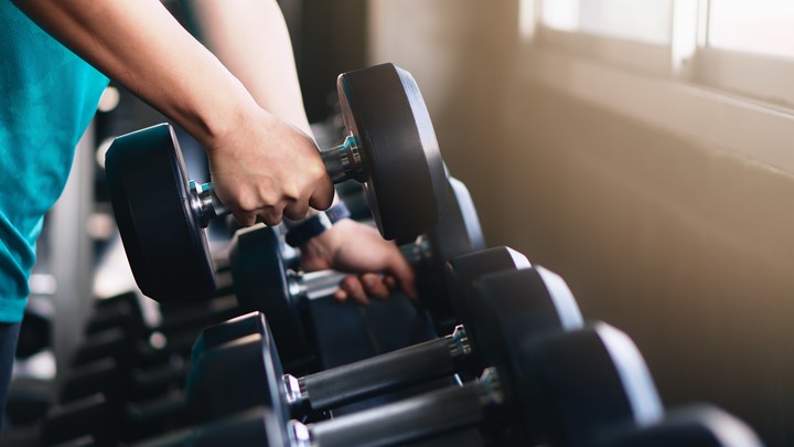 Close up photo of a person picking up a dumb bell.