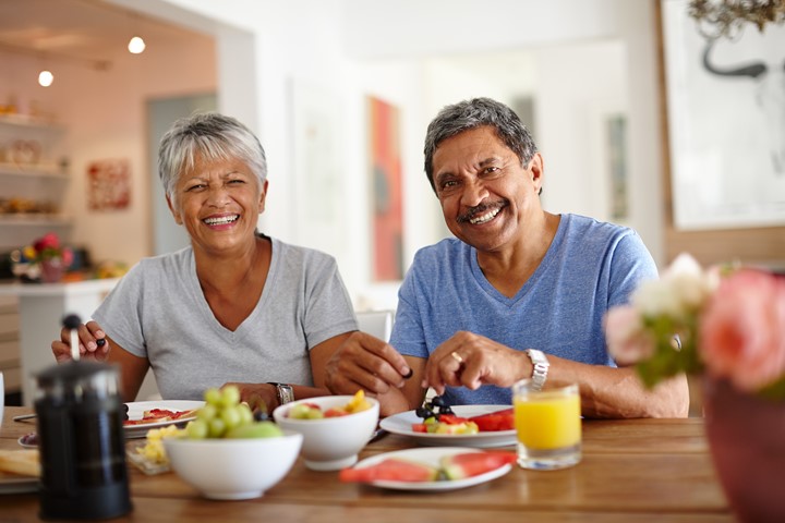 Photo of two people sitting at a table with fruit.