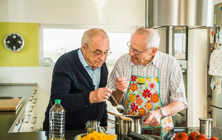 Two older men cooking together at home