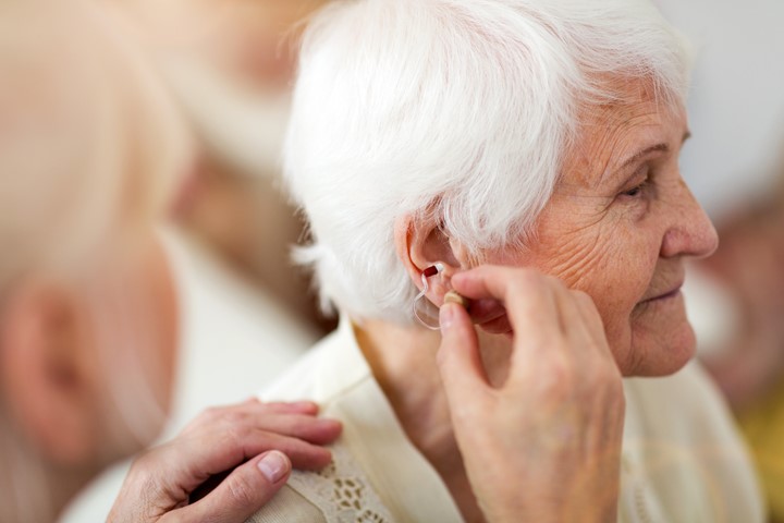 Nurse helping older woman with a hearing aid