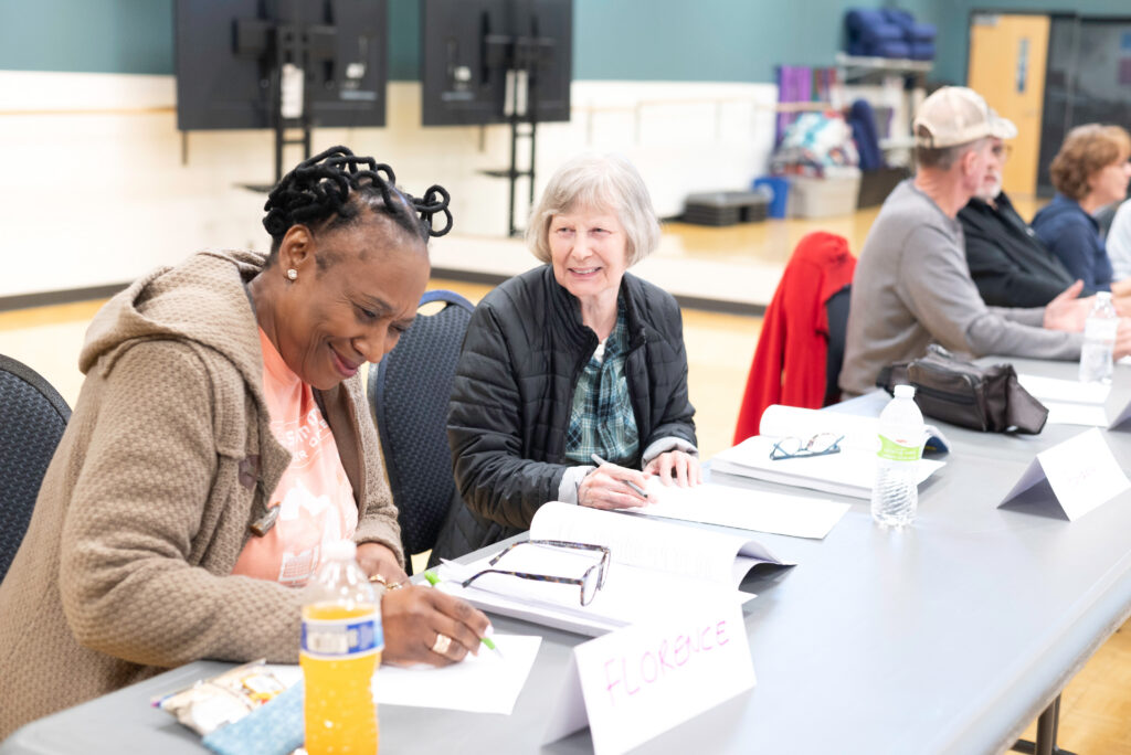 Photo of two people talking and taking notes at a table.