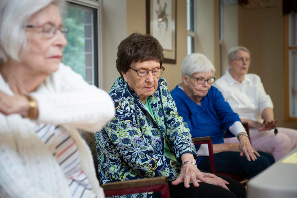 Photo of four people crossing their arms while seated.