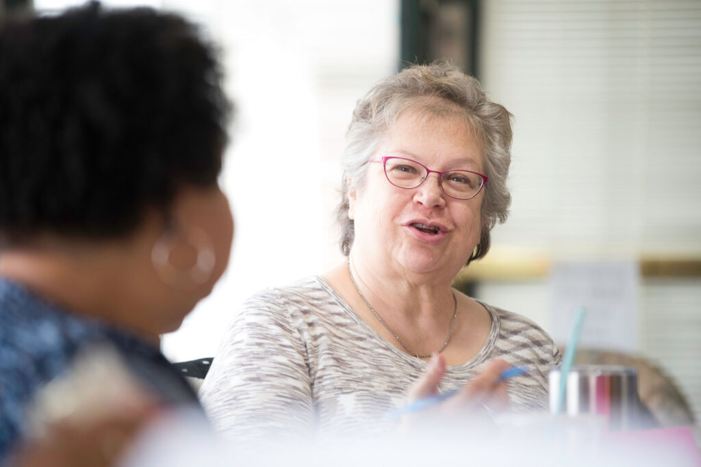 An older woman talking in a group setting.