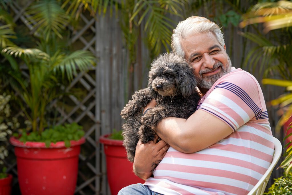 Photo of an older adult hugging a small dog.